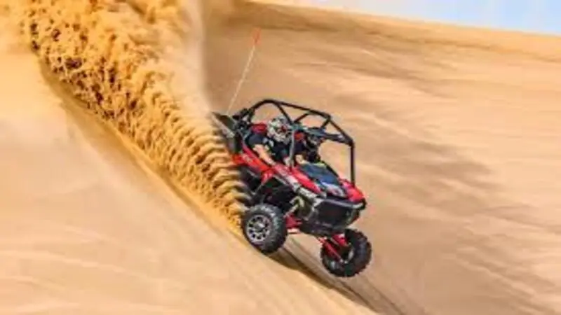 Dune buggy driving on the Red Dunes in Dubai desert with sunset background