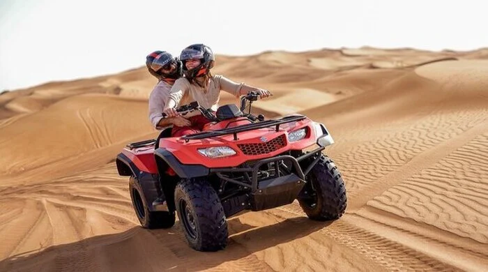 Desert safari quad biking in Dubai with safety gear on red sand dunes