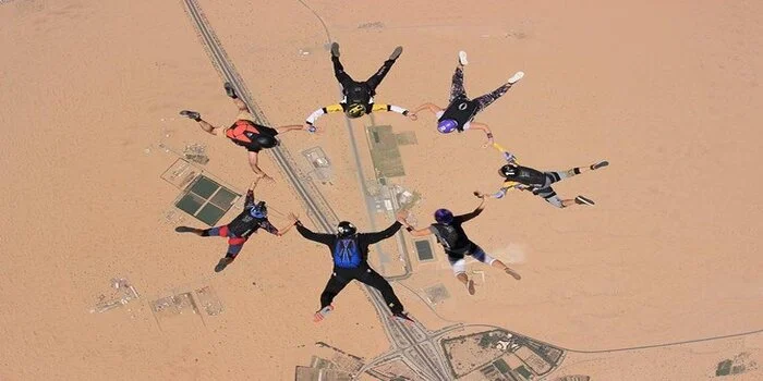 Skydiver above Dubai desert with dunes below during desert safari skydiving combo tour