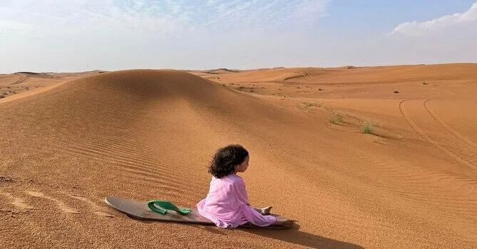 Children enjoying sandboarding ride at a kid-friendly Dubai desert safari camp